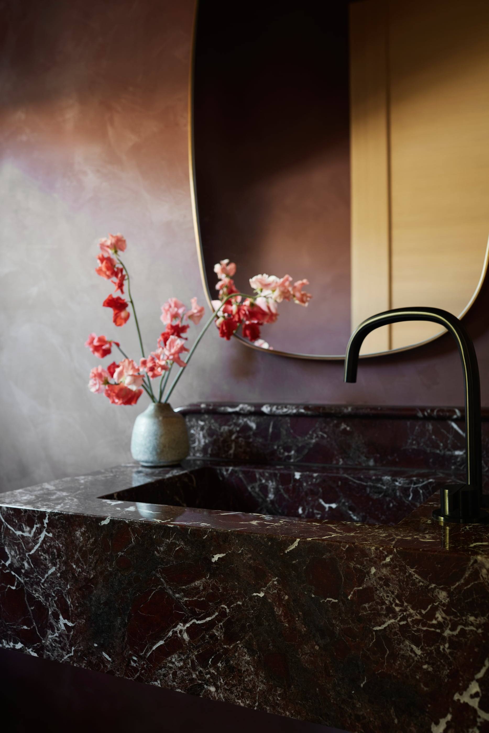 Burgundy Roman clay walls and a Rosso Levanto marble vanity