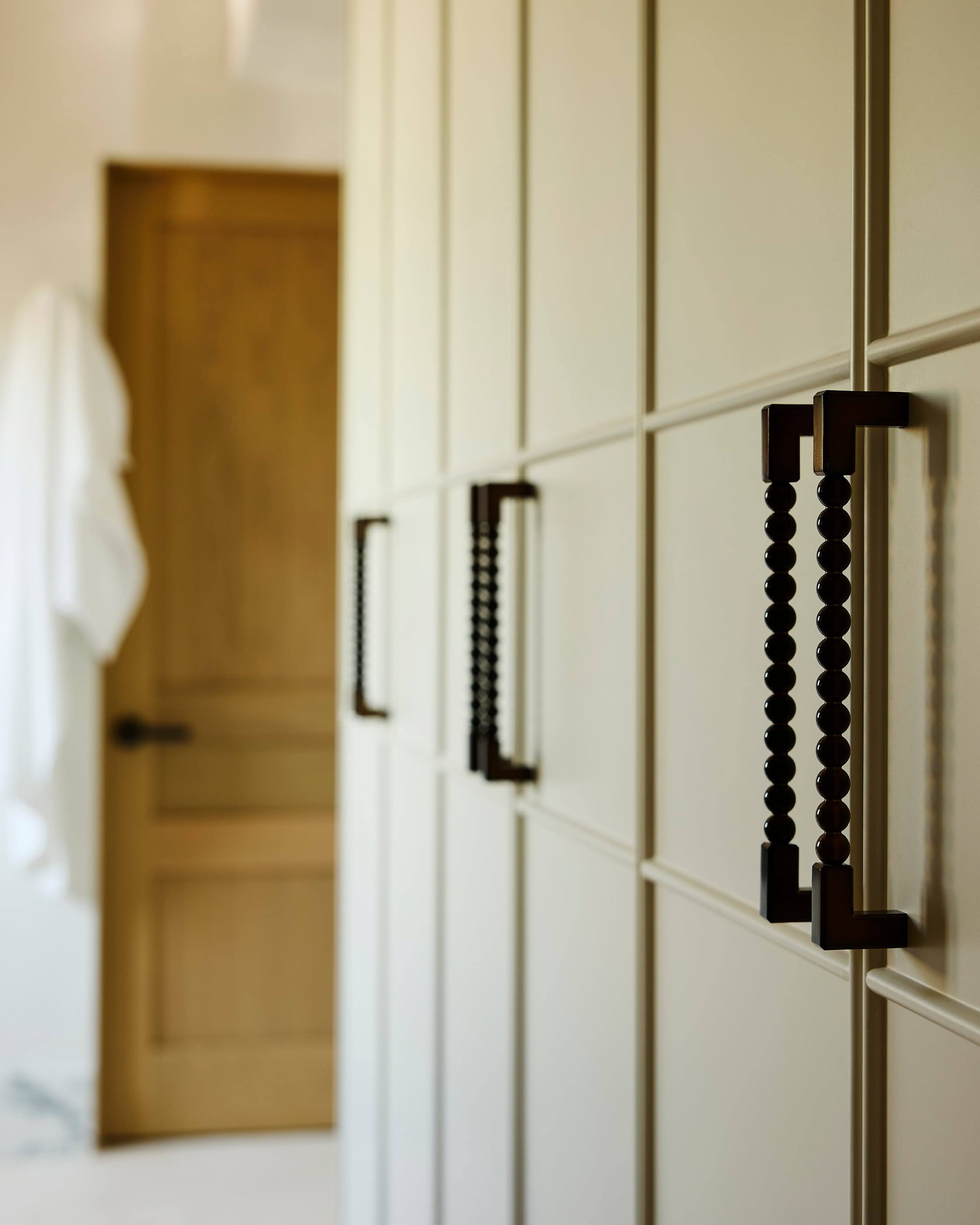 Beaded bronze pulls on a paneled closet wall