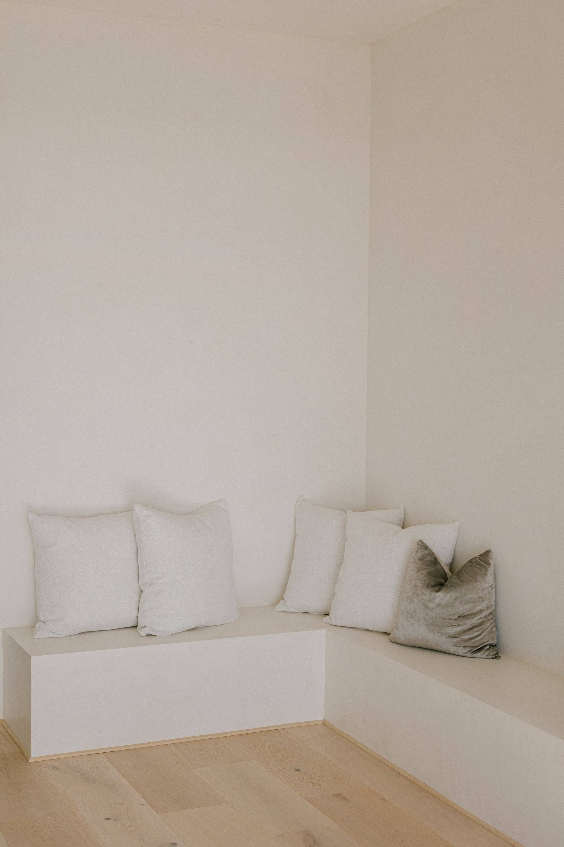 Built-in plaster corner bench with linen cushions