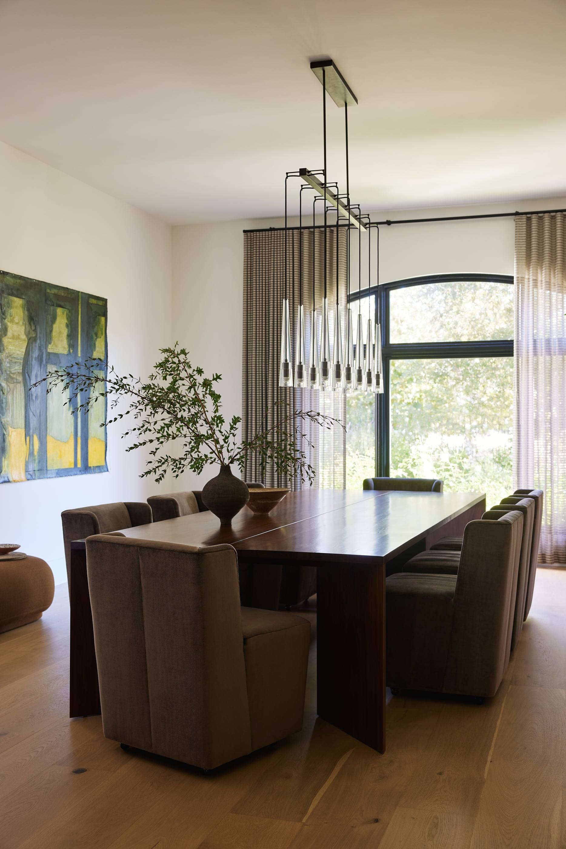 Dining room with a long table beneath a cascade of glass pendants