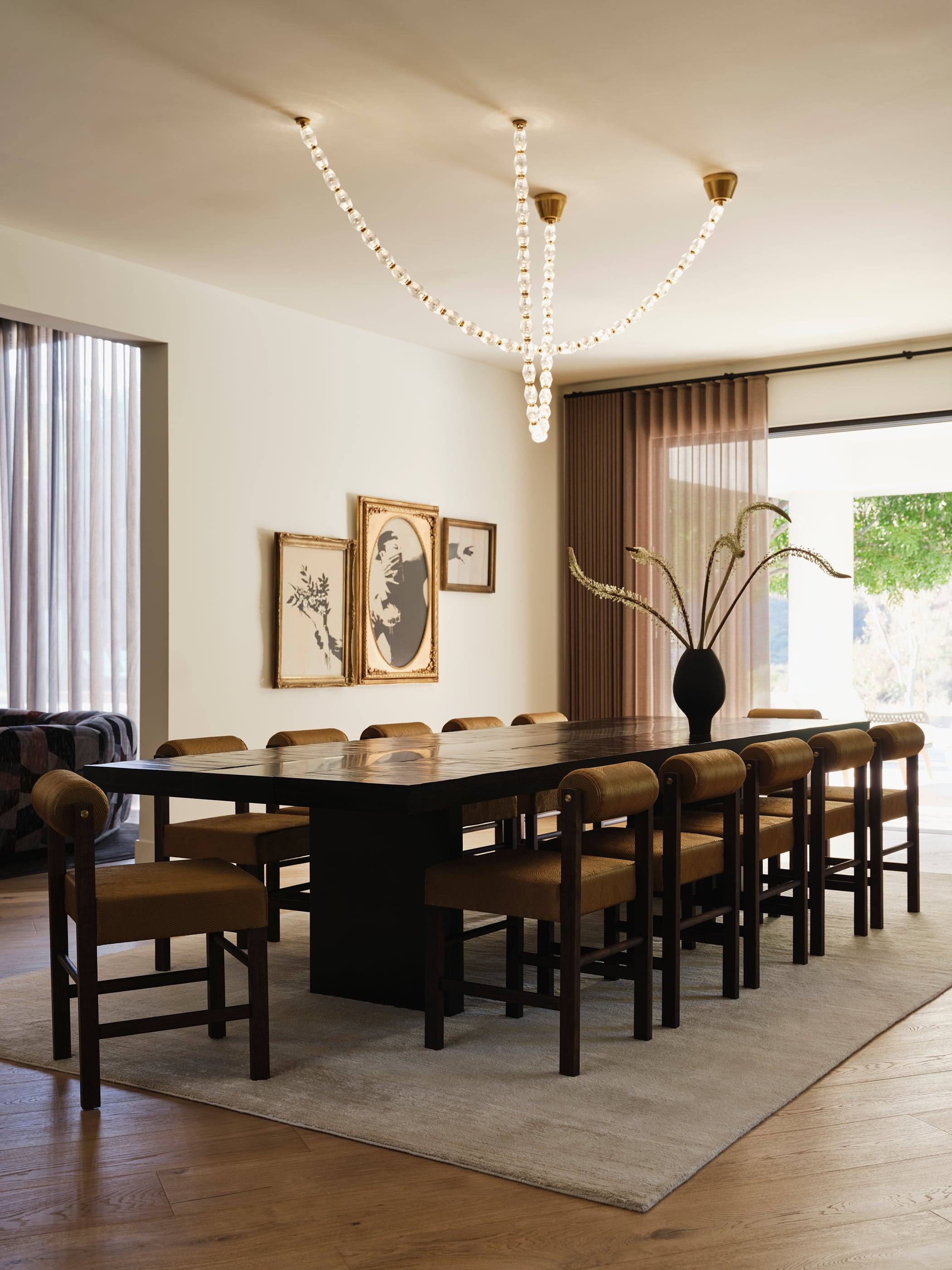 Dining room with a long table beneath a sculptural beaded chandelier