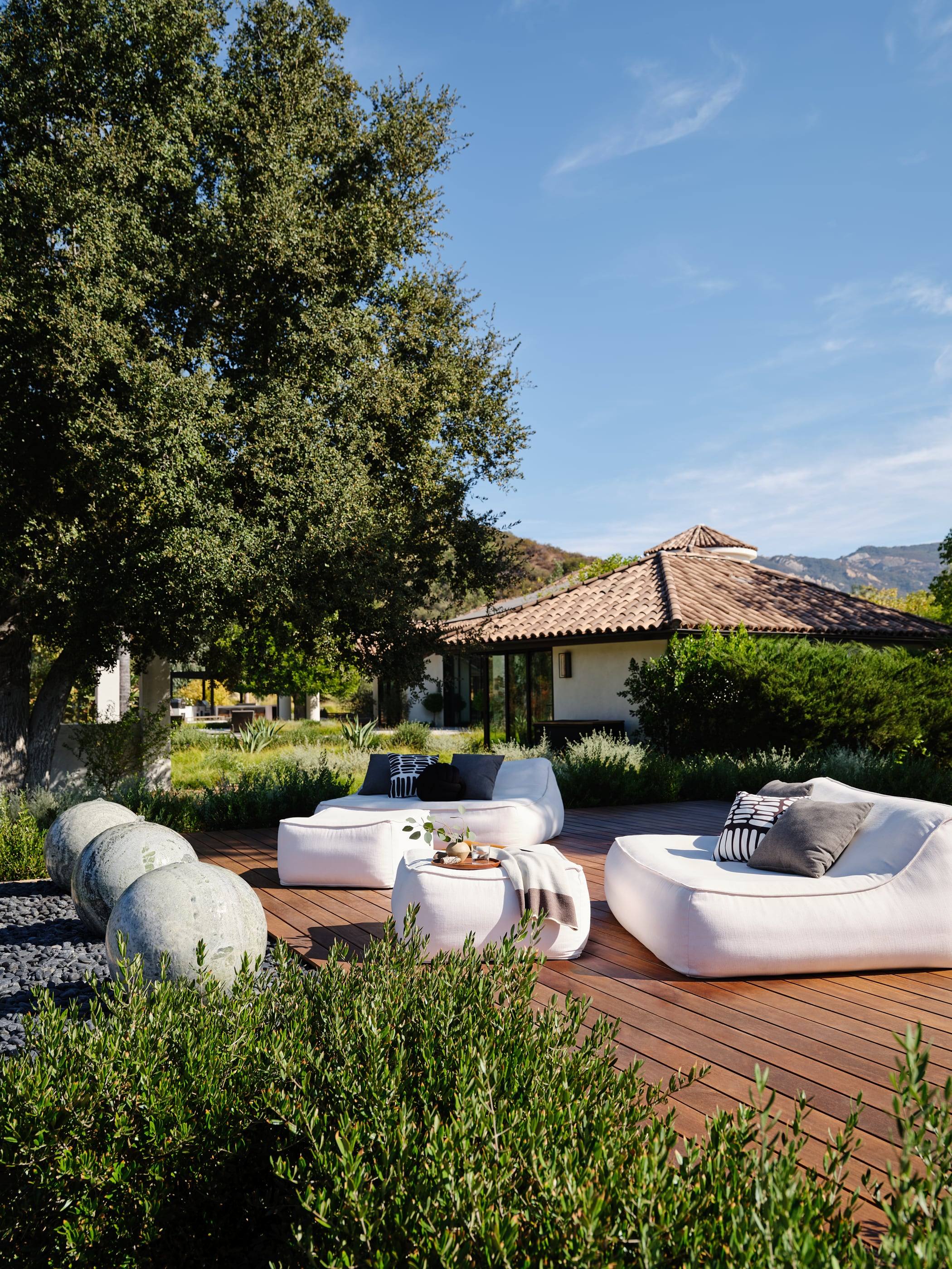 Garden lounge with white outdoor sofas and sculptural stools
