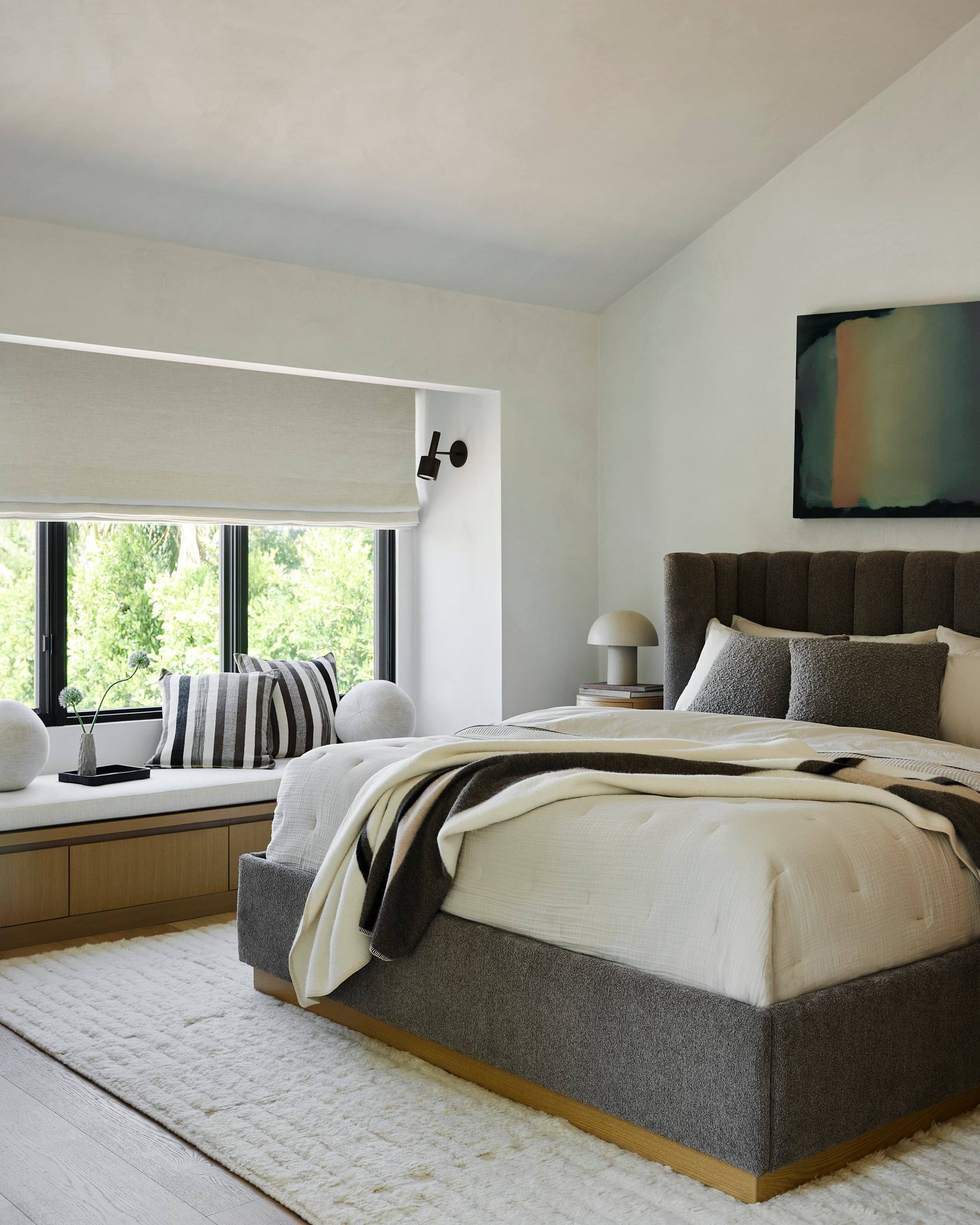 Bedroom with a channel-tufted bed and a window seat facing the trees