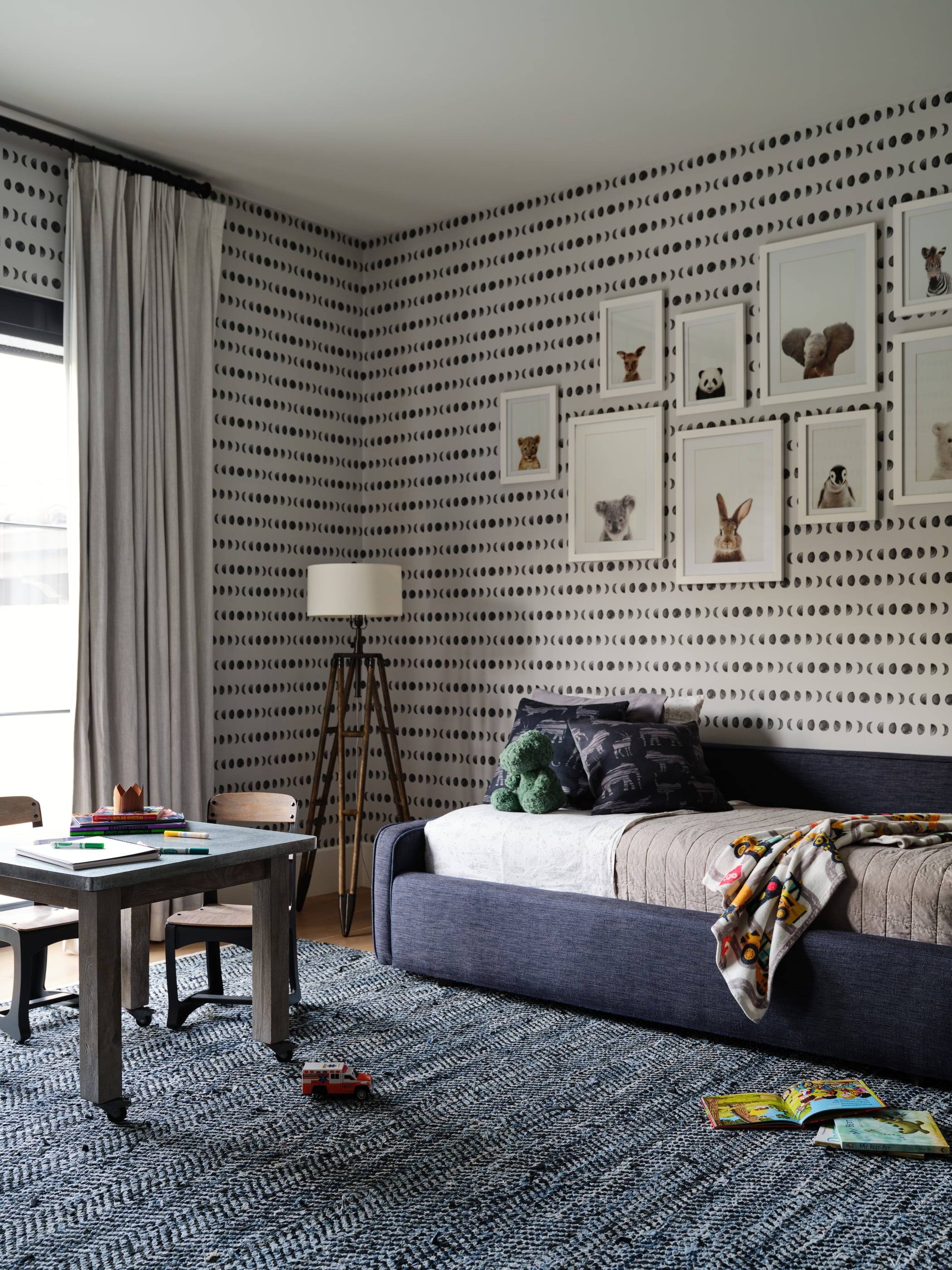 Child's bedroom with graphic wallpaper and a gallery of framed prints