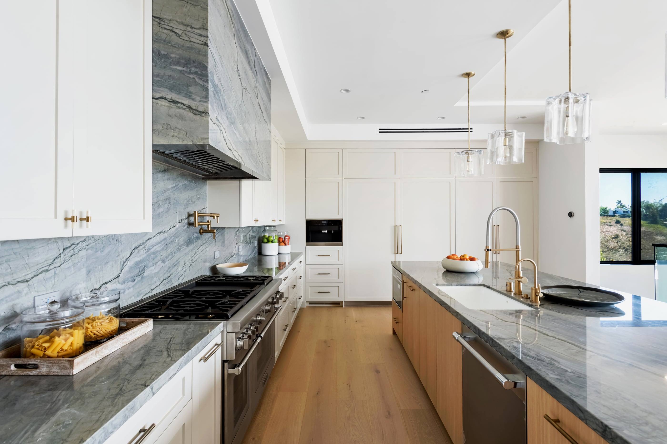Kitchen with a quartzite backsplash and range hood looking toward the view