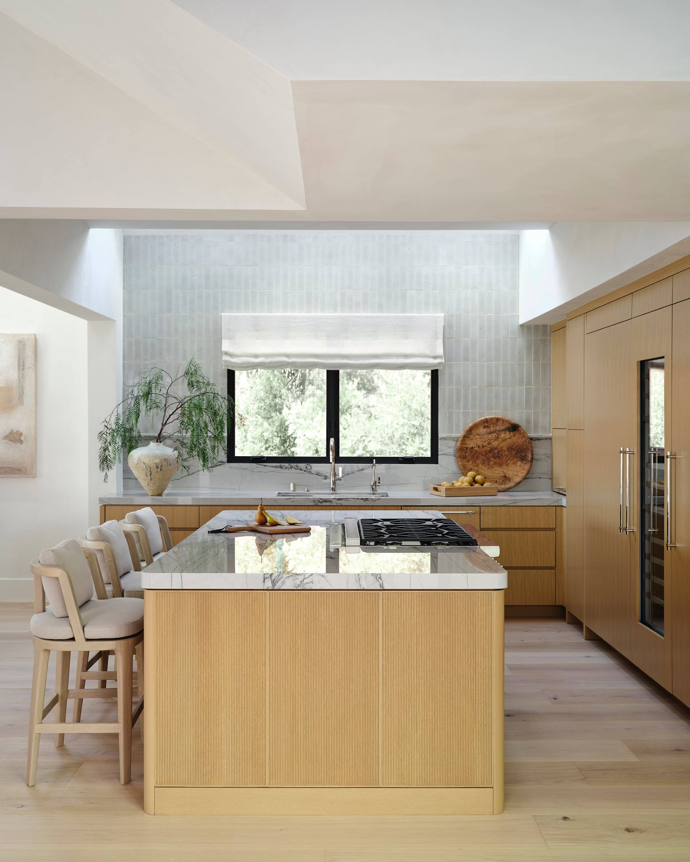 White oak kitchen with a marble-topped island under a skylight