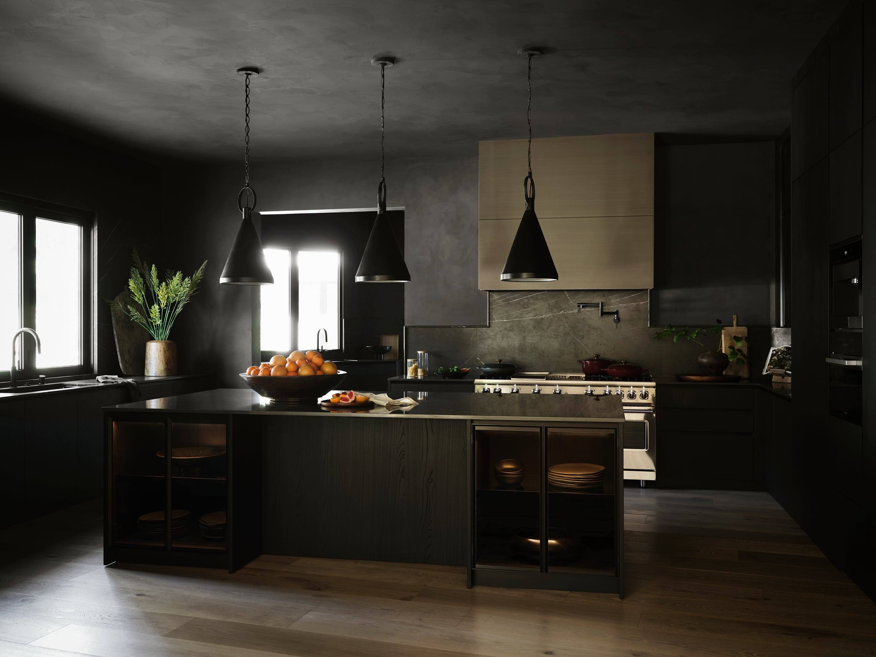 Black kitchen with plaster walls and three black pendant lights