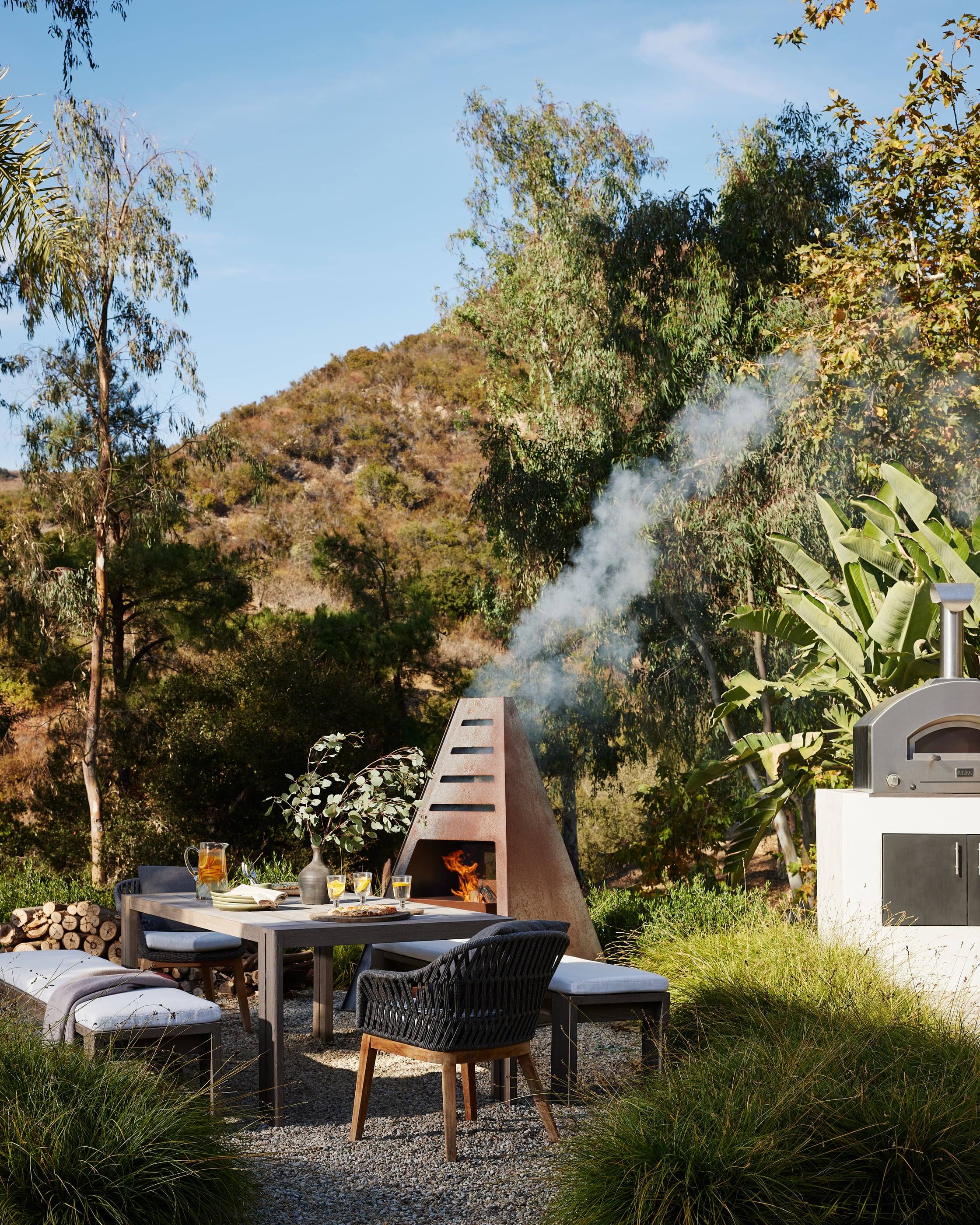 Outdoor dining beside a pizza oven and sculptural fireplace