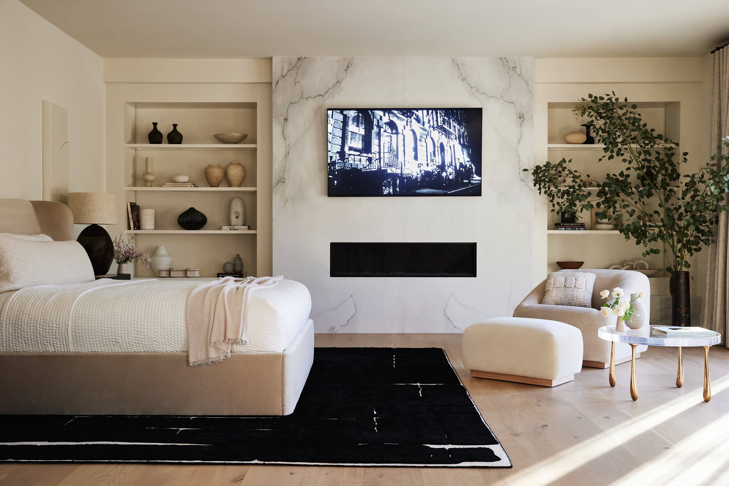 Primary bedroom with a marble fireplace wall and built-in shelving