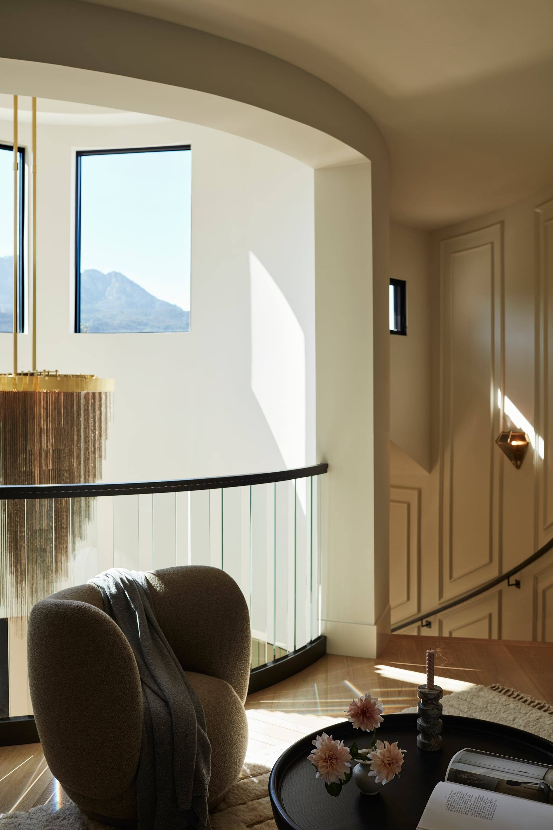 Curved stair landing with a sculptural chair and a mountain view