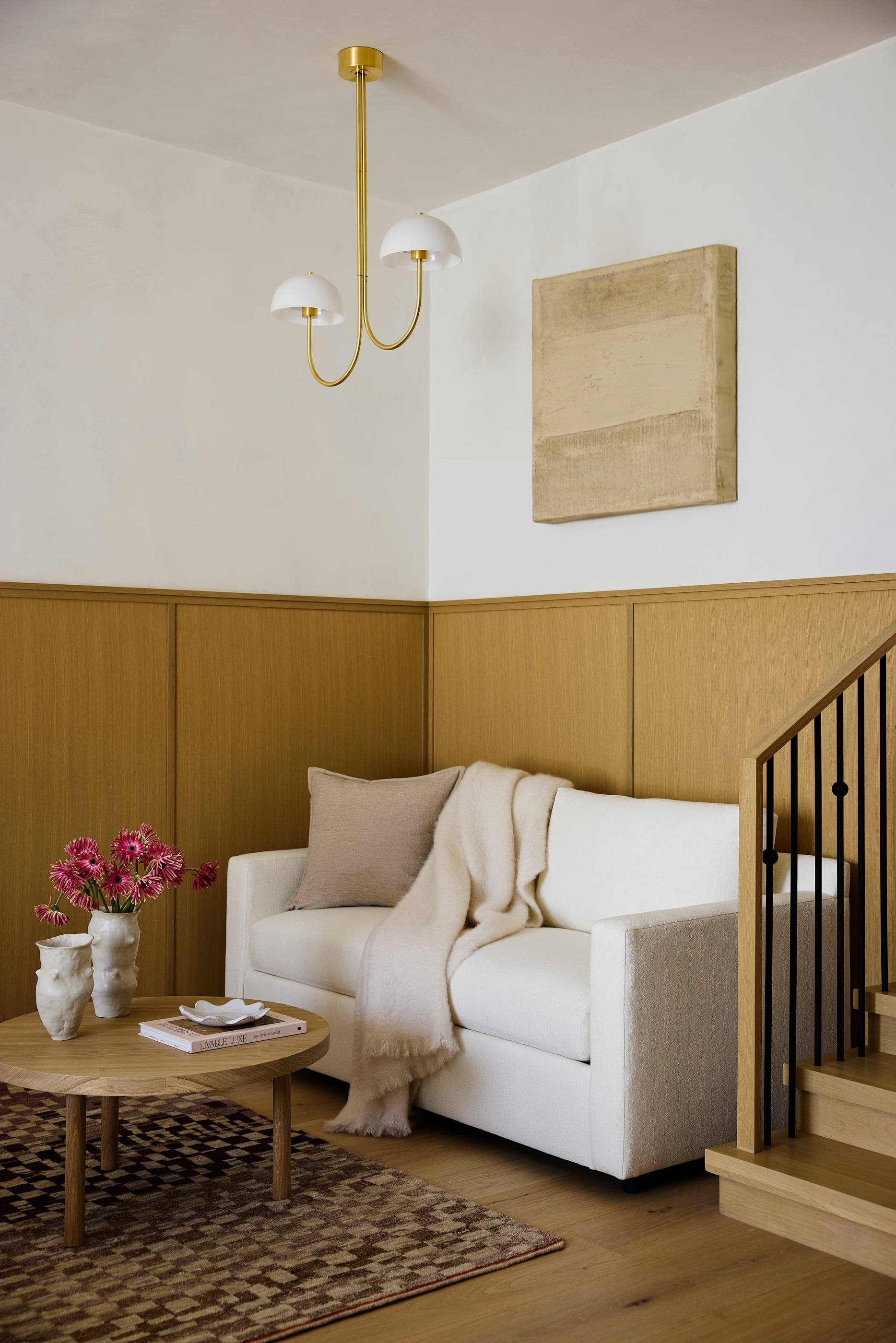 Reading nook with an oak wainscot and brass pendant beside the stair
