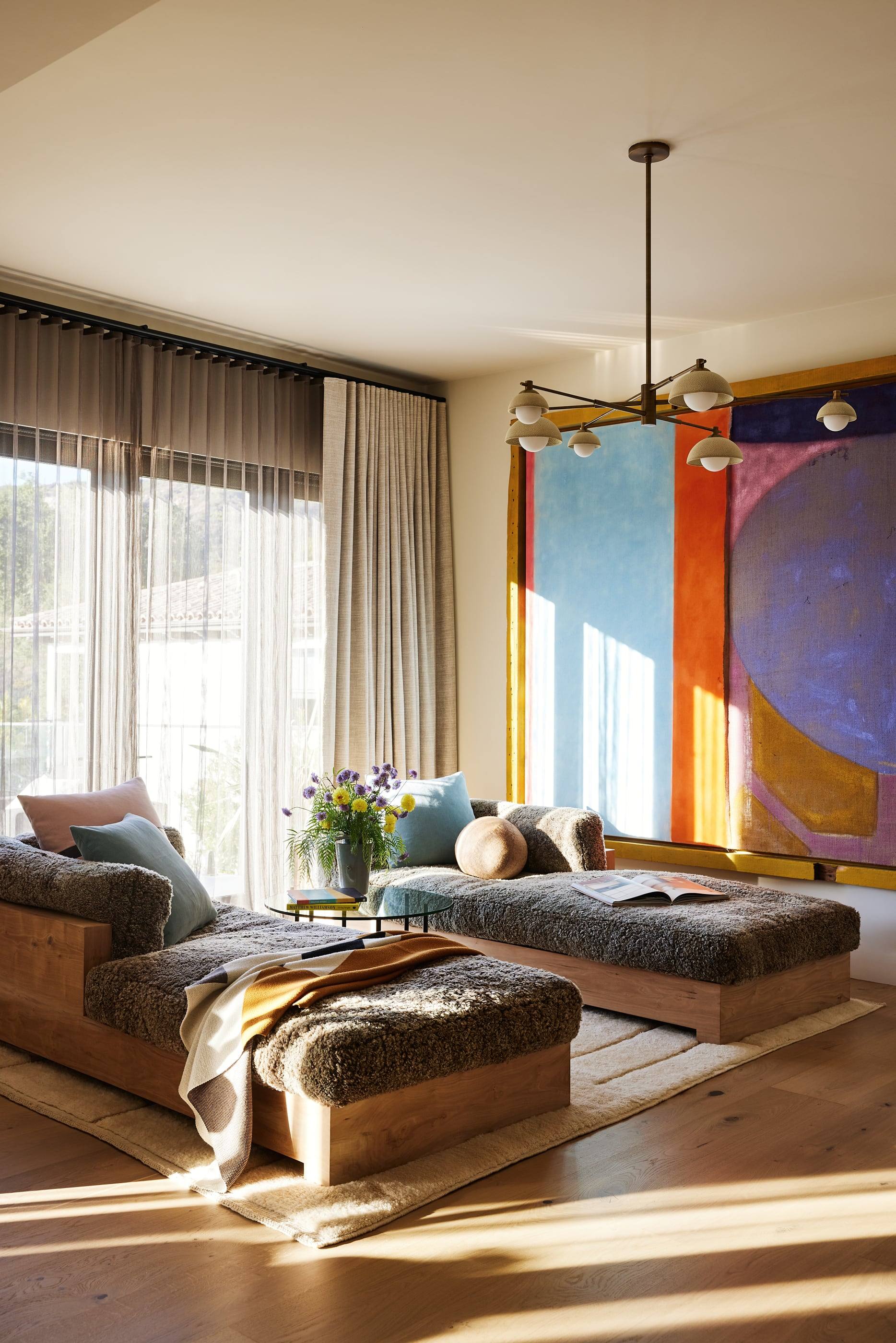 Sunlit lounge with shearling chaises beneath a vivid abstract painting