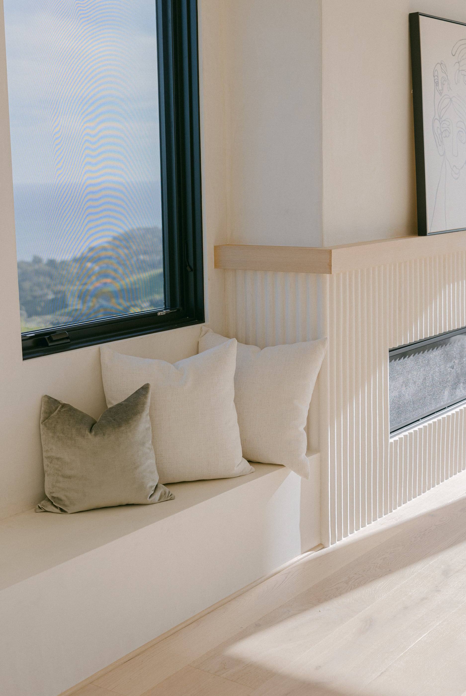 Plaster window seat beside a fluted fireplace with an ocean view